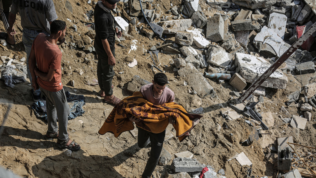 Un hombre lleva un cuerpo cubierto con una manta durante una operación de búsqueda y rescate en el campo de refugiados de Jabalia, en la ciudad de Gaza, el 1 de noviembre de 2023. Ali Jadallah / Anadolu Agency / Gettyimages.ru