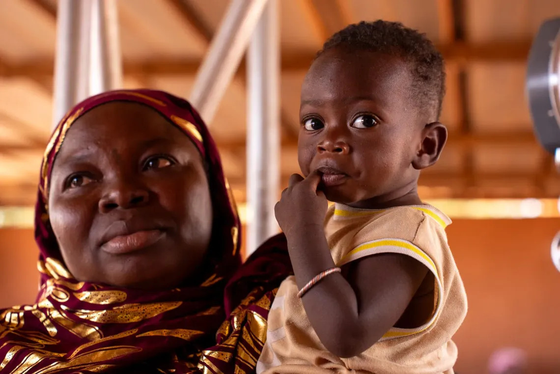 UNICEF/UNI829225 Una mujer carga a su hijo en un centro de salud en Ouagadougou, Burkina Faso.