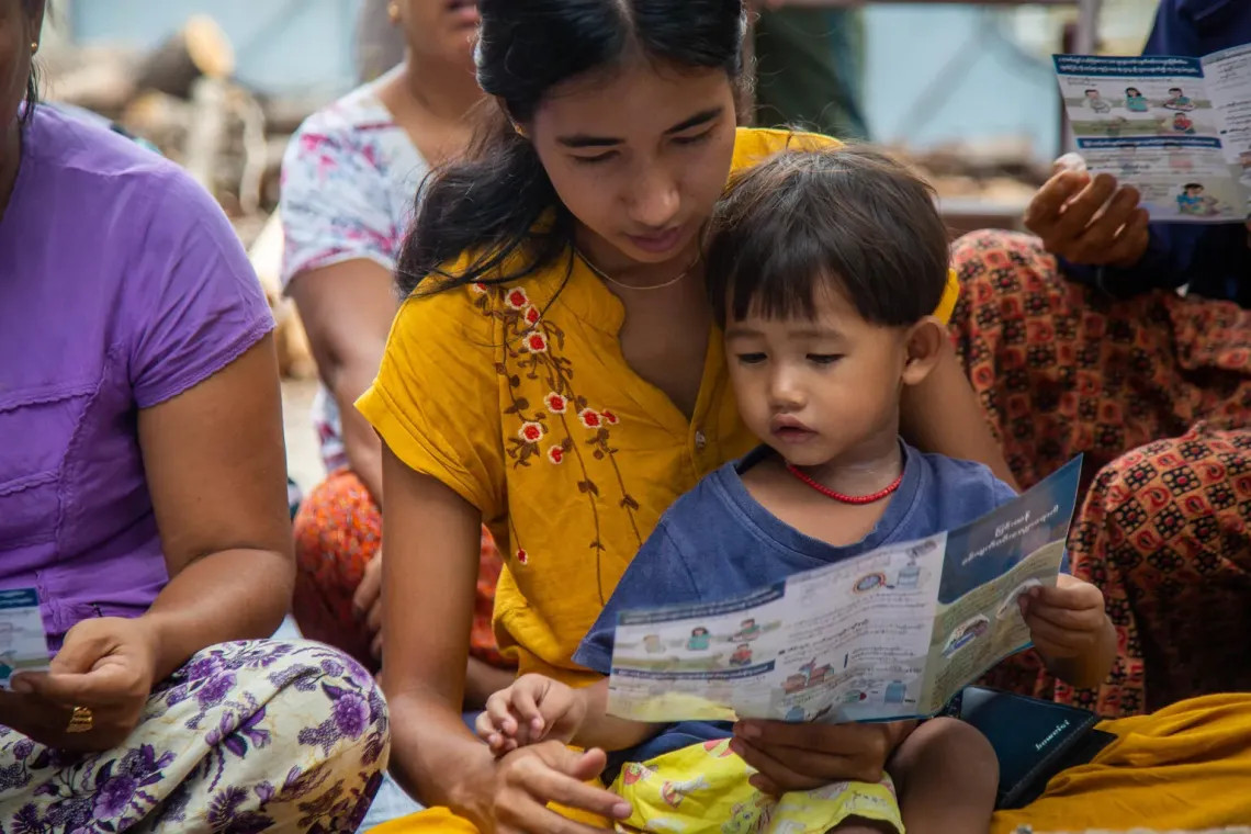 UNICEF/UNI825843/Htet Una madre lee un panfleto educativo de prevención de diarrea para familias desplazadas en la región de Mandalay, Myanmar.